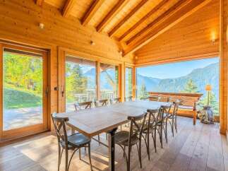 Experience breathtaking mountain views from this stunning dining room, featuring a large wooden table and chairs perfect for family gatherings.