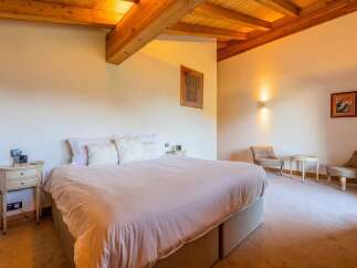 Experience ultimate comfort in this beautifully appointed bedroom, featuring a plush king-size bed with crisp white linens and decorative pillows.