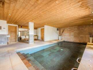 Indulge in relaxation in this luxurious indoor swimming pool area, featuring a spacious pool with easy-access steps and a serene ambiance.