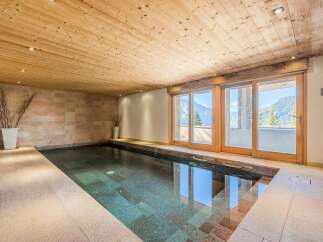 Indulge in relaxation at this indoor swimming pool, featuring a stunning wooden ceiling and tiled walls that create a warm, inviting atmosphere.