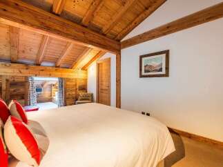Experience rustic charm in this cozy bedroom featuring a beautifully crafted wooden ceiling with exposed beams, creating a warm and inviting atmosphere.