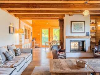 Experience rustic charm in this inviting living room, featuring exposed wooden beams and a cozy fireplace.