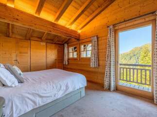 Experience cozy mountain living in this charming wooden bedroom, featuring a comfortable bed and ample built-in storage.
