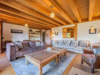 Experience rustic charm in this inviting living room, featuring a warm wooden beamed ceiling and cozy seating arrangements.