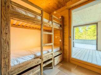 Experience cozy comfort in this charming room featuring rustic wooden bunk beds with built-in storage drawers.
