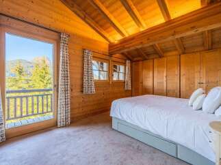 Experience breathtaking mountain views from this charming wooden chalet bedroom.