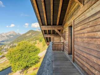 Experience breathtaking mountain views from the expansive wooden balcony of this charming chalet.