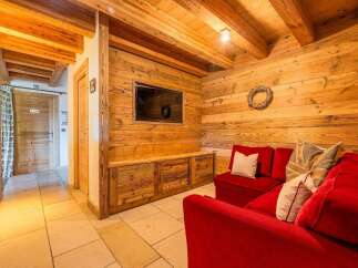 Experience rustic charm in this mountain retreat, featuring a cozy living area with rich wood paneling and a plush red sofa.
