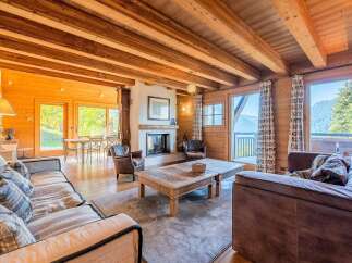 Experience the epitome of mountain living in this stunning chalet, featuring a spacious living area with a cozy fireplace and exposed wooden beams.