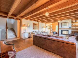 Experience rustic charm and modern comfort in this spacious living area, featuring a stunning exposed wooden beam ceiling and a cozy fireplace.
