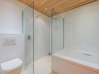 Experience modern luxury in this stunning bathroom featuring a sleek, frameless glass shower enclosure and a deep soaking bathtub.