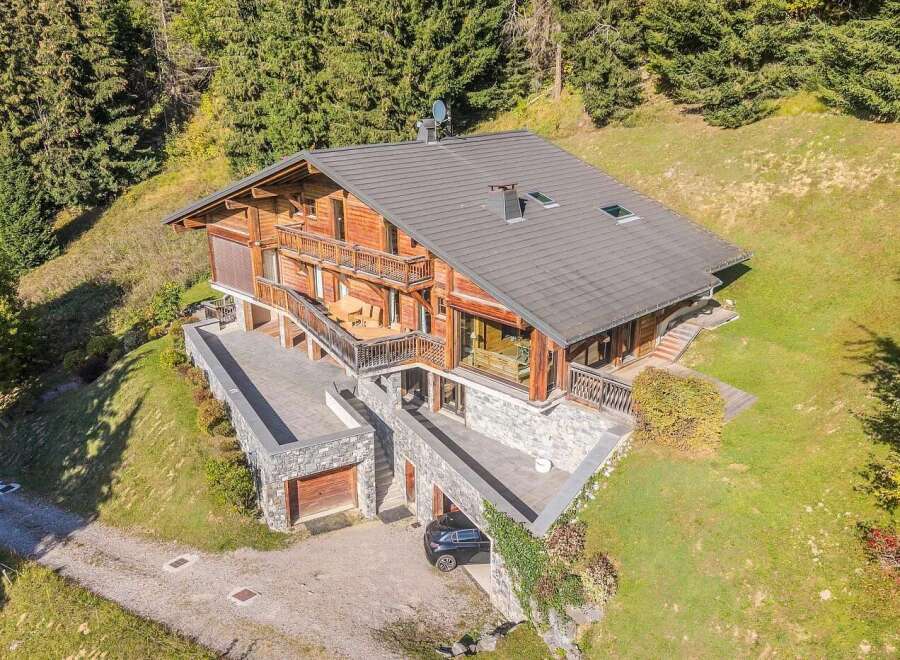 Discover this stunning wooden chalet nestled amidst a lush forest, offering breathtaking mountain views.