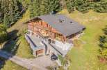 Discover this stunning wooden chalet nestled amidst a lush forest, offering breathtaking mountain views.