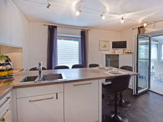 Experience modern living in this stylish kitchen featuring a sleek island with a built-in sink and ample counter space, perfect for meal preparation and casual dining.