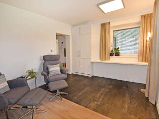 Discover this inviting living space featuring comfortable grey armchairs with ottomans, perfect for relaxation.