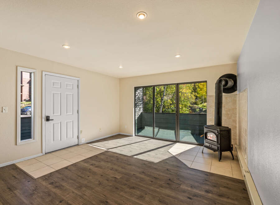 Cozy up by the cast iron wood-burning stove in this inviting living space, featuring a wall of windows that flood the room with natural light.