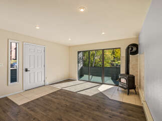 Cozy up by the cast iron wood-burning stove in this inviting living space, featuring a wall of windows that flood the room with natural light.