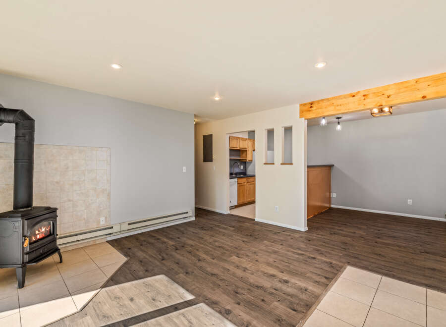 Cozy up by the fireplace in this inviting living space, featuring a charming wood-burning stove and warm, wood-look flooring.