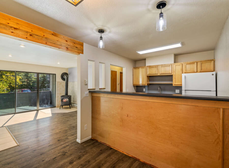 Step into this inviting living space featuring a cozy wood-burning stove and expansive sliding glass doors that open to a lush, tree-filled view.