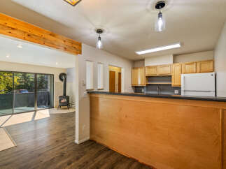 Step into this inviting living space featuring a cozy wood-burning stove and expansive sliding glass doors that open to a lush, tree-filled view.