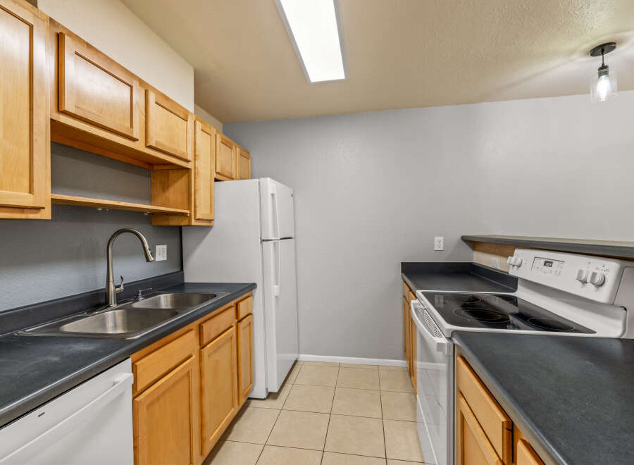 This kitchen features light wood cabinets providing ample storage space, complemented by dark countertops.