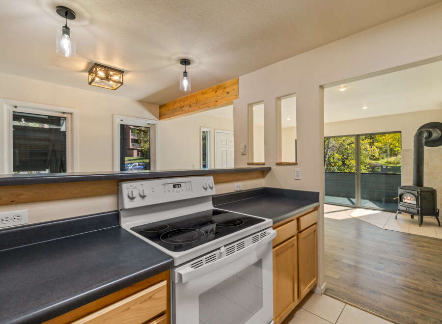 This kitchen features a white electric range with a black stovetop, complemented by dark countertops and light wood cabinetry.