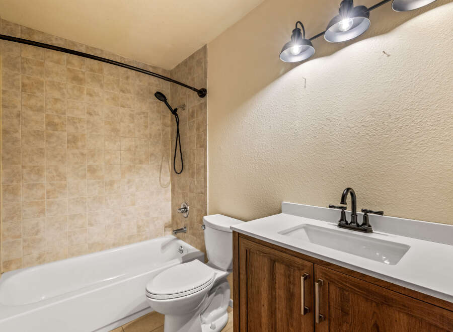 This bathroom features a classic white bathtub and toilet, complemented by warm-toned tiled walls for a timeless look.