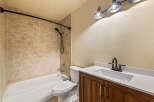 This bathroom features a classic white bathtub and toilet, complemented by warm-toned tiled walls for a timeless look.