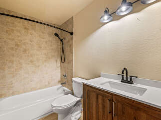 This bathroom features a classic white bathtub and toilet, complemented by warm-toned tiled walls for a timeless look.