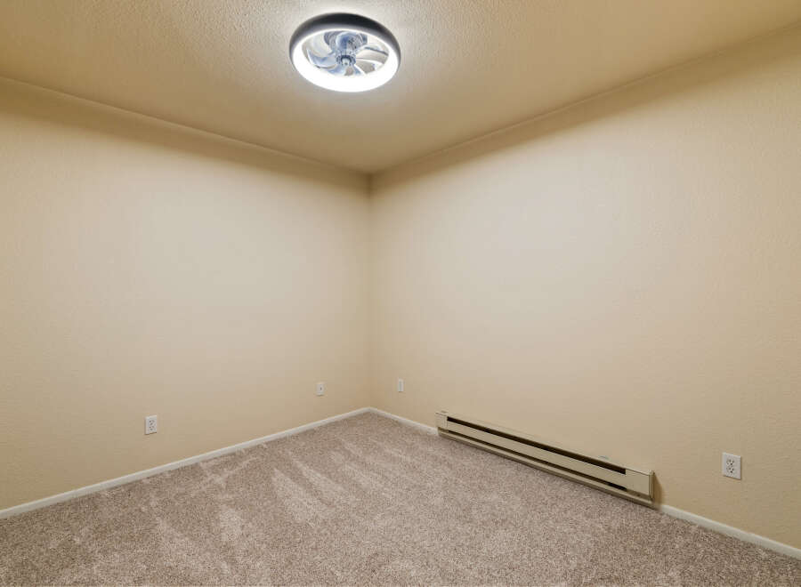 This empty room features neutral beige walls and plush carpeting, creating a blank canvas for your personal style.
