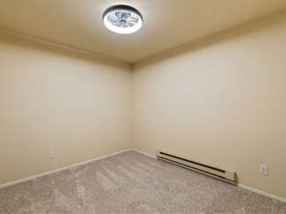 This empty room features neutral beige walls and plush carpeting, creating a blank canvas for your personal style.