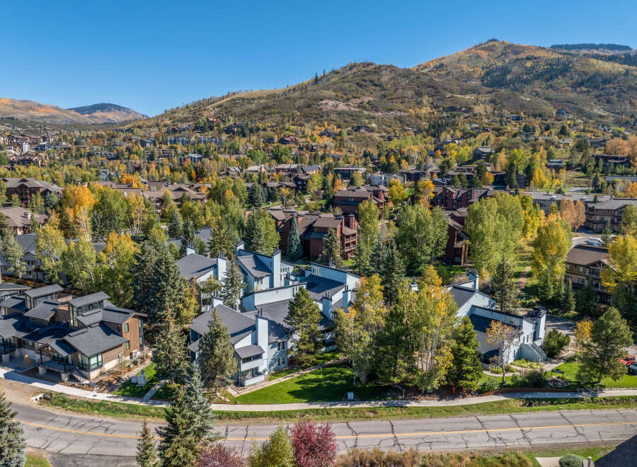 Experience the beauty of autumn in this stunning aerial view of a residential community nestled amidst vibrant fall foliage.
