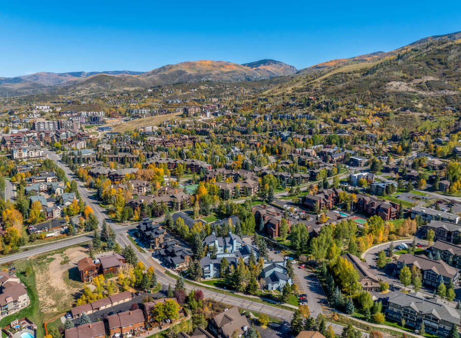 Experience the beauty of autumn in this stunning aerial view of a mountain town, showcasing a vibrant tapestry of fall foliage.