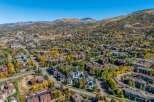 Experience the beauty of autumn in this stunning aerial view of a mountain town, showcasing a vibrant tapestry of fall foliage.