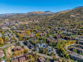 Experience the beauty of autumn in this stunning aerial view of a mountain town, showcasing a vibrant tapestry of fall foliage.
