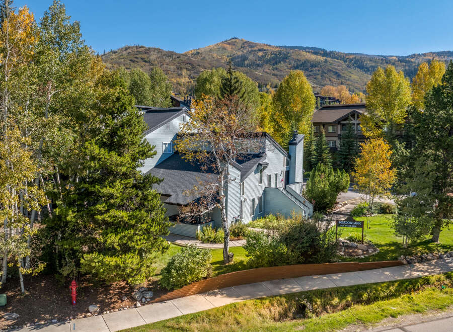 Experience the charm of autumn in this picturesque setting, featuring a light blue multi-story building nestled amongst vibrant fall foliage.
