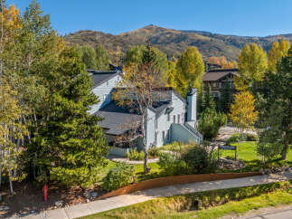 Experience the charm of autumn in this picturesque setting, featuring a light blue multi-story building nestled amongst vibrant fall foliage.