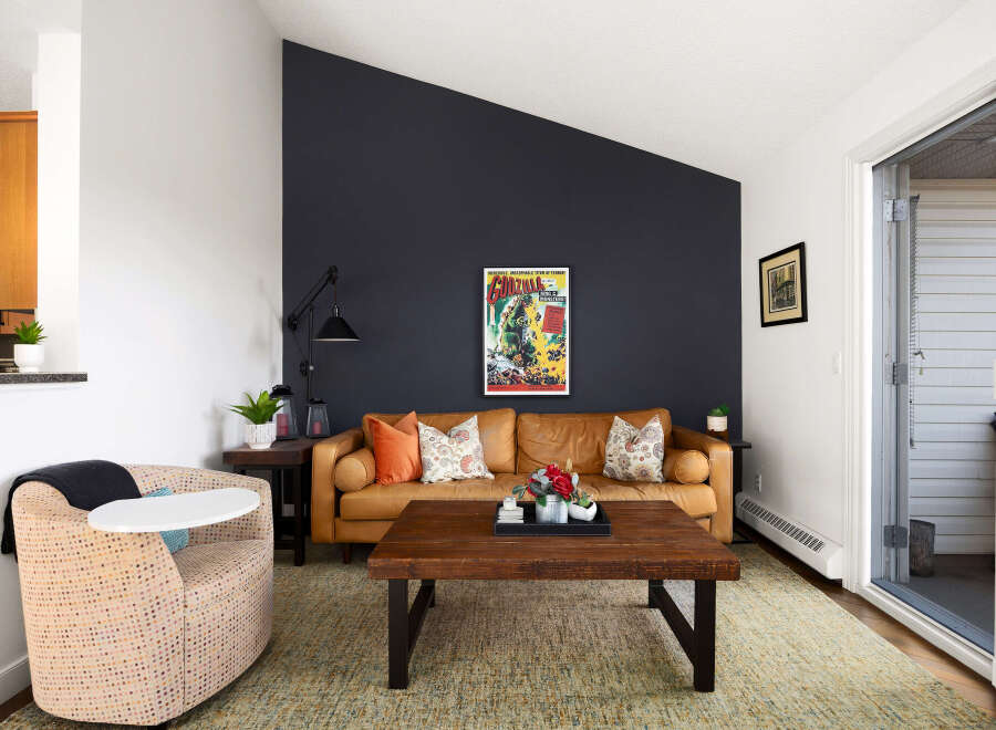 Step into this inviting living room featuring a warm, caramel-colored leather sofa complemented by a striking dark accent wall.