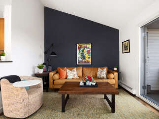 Step into this inviting living room featuring a warm, caramel-colored leather sofa complemented by a striking dark accent wall.