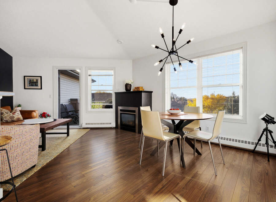 This open-concept living and dining area boasts a modern aesthetic with a sleek black fireplace and a striking Sputnik chandelier.