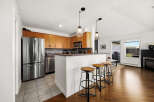 Experience modern living in this beautifully appointed kitchen, featuring sleek stainless steel appliances, warm wood cabinetry, and a convenient breakfast bar with stylish stools.