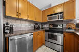 This kitchen boasts modern stainless steel appliances, including a dishwasher, oven, and microwave, complemented by sleek wooden cabinetry.