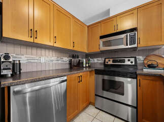This kitchen boasts modern stainless steel appliances, including a dishwasher, oven, and microwave, complemented by sleek wooden cabinetry.