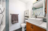 This modern bathroom features a sleek white vessel sink atop a warm wood vanity, complemented by a large, ornate mirror.