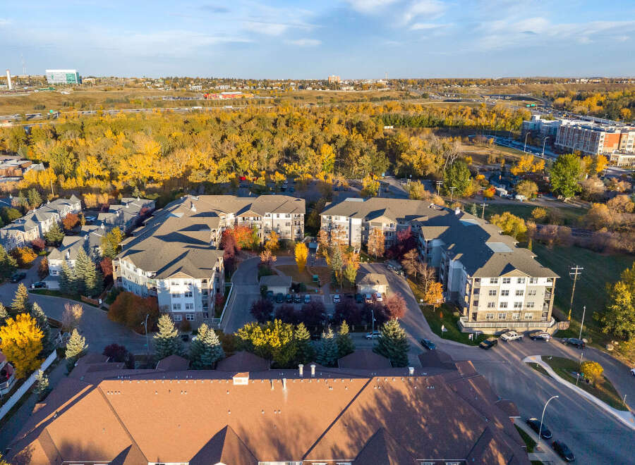 Experience modern living in this aerial view of a contemporary apartment complex nestled amidst vibrant autumn foliage.
