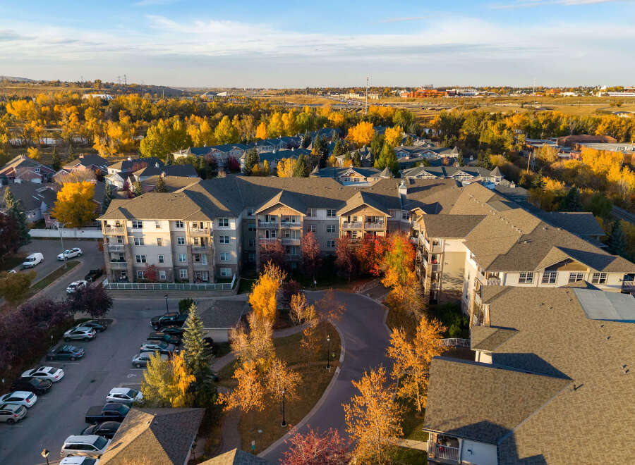 Experience autumn's splendor from this aerial view of a modern apartment complex nestled amongst vibrant fall foliage.