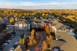 Experience autumn's splendor from this aerial view of a modern apartment complex nestled amongst vibrant fall foliage.