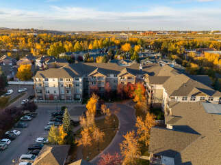 Experience autumn's splendor from this aerial view of a modern apartment complex nestled amongst vibrant fall foliage.