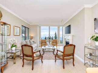 Experience breathtaking ocean views from this elegant living room, featuring a cozy fireplace and a large picture window.