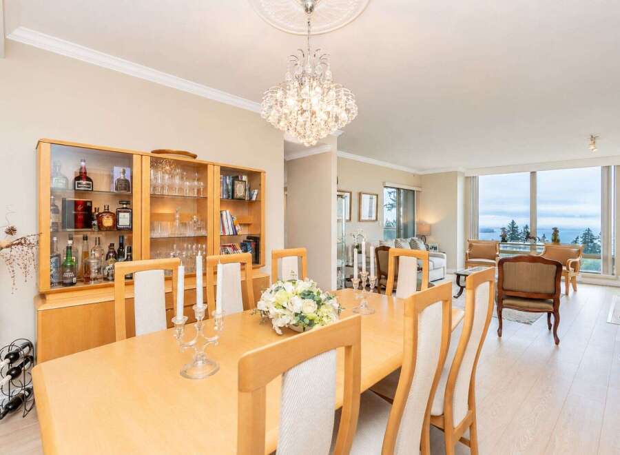 Experience elegant dining in this beautifully appointed space, featuring a large wooden table set for gatherings and a stunning crystal chandelier overhead.